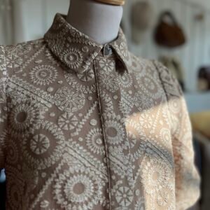 Cette robe courte associe élégance et modernité avec son tissu brodé texturé et son coloris Tannin, un beige intemporel. Son col chemise structuré apporte une touche sophistiquée, tandis que ses manches courtes bouffantes ajoutent du volume et de la féminité. Sa coupe fluide et droite assure confort et légèreté. Polyvalente, elle se porte aussi bien avec des bottines, des sandales ou des baskets pour un style adapté à chaque occasion.