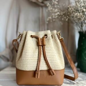 Cette bourse en raphia est l’accessoire idéal pour accompagner vos journées ensoleillées. Alliant élégance et naturel, elle associe du cuir de vachette grainé à du raphia tressé, offrant un style à la fois chic et décontracté.